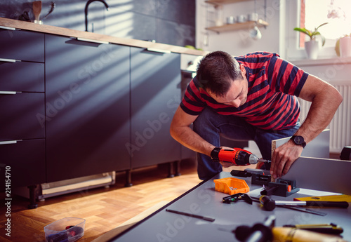Billede på lærred Woman building kitchen and using a cordless drill