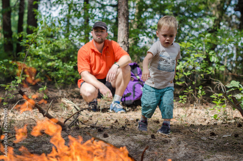 Dad and son make a big fire in the forest