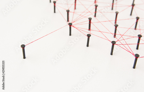 social media  Communications Network  one person connected to the rest networks. Network simulation on white paper linked together created by black nail and red thread with copy space