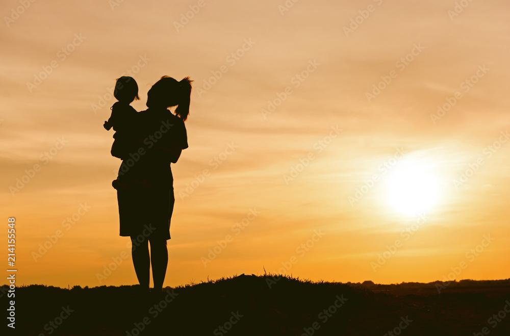 Silhouette of mother and daughter lifting child in air over scenic sunset sky at riverside. relaxation time and happiness