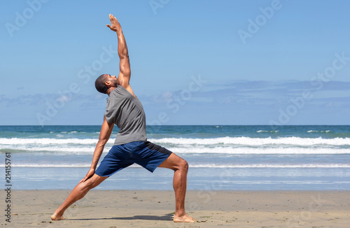 Athletic man at the beach in Reverse Warrior yoga pose