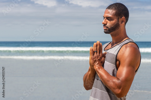 Athletic man at the beach in Prayer yoga position.