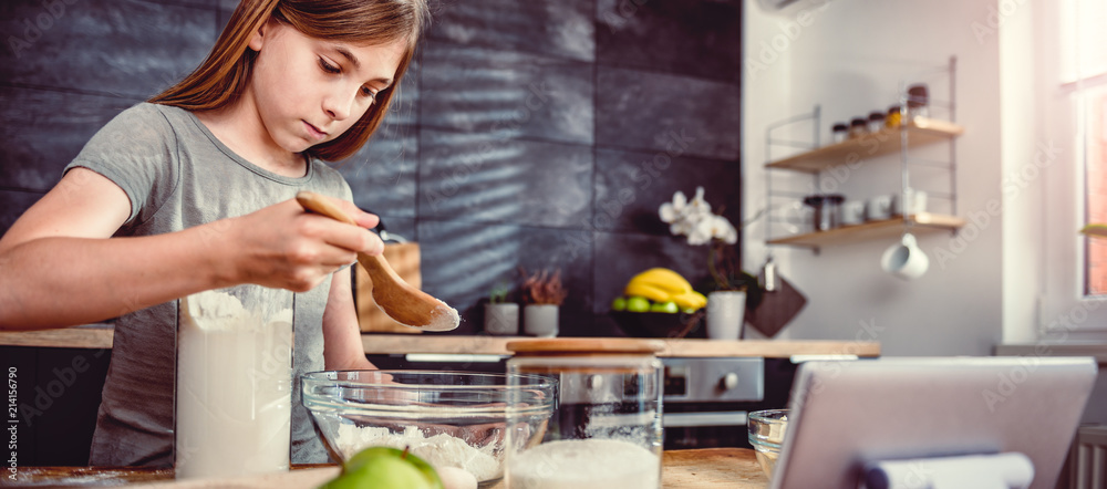 Girl adding flour into mixing bowl Girl adding flour into mixing bowl
