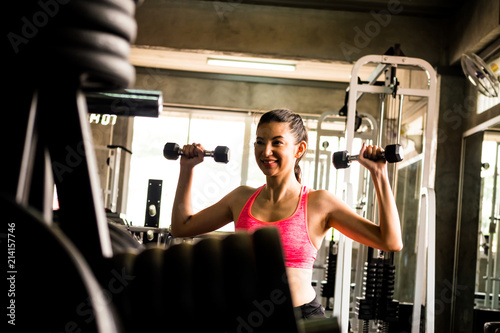 Attractive young woman exercising building muscles at the gym