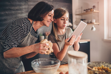 Mother and daughter searching apple pie recipe on the tablet