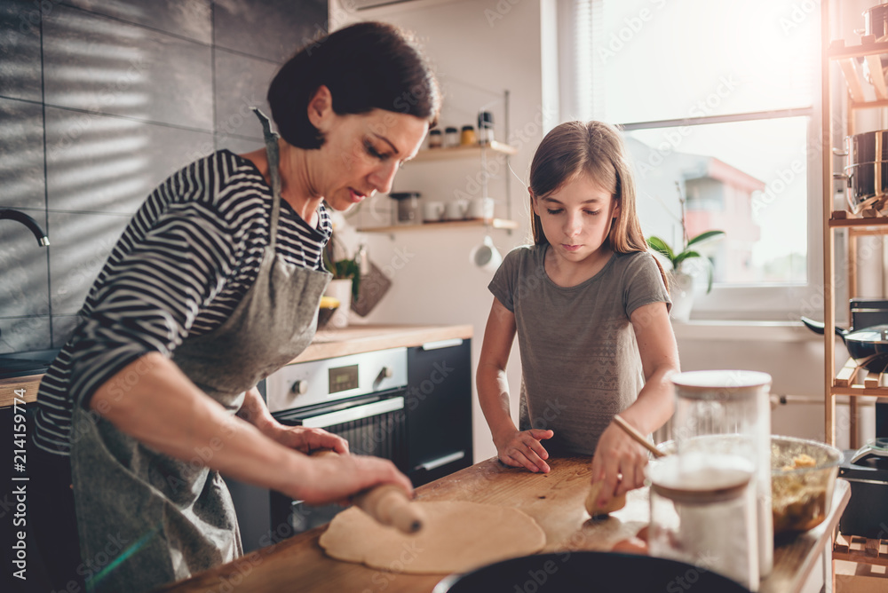 Mother and daughter kneading dough on the wooden table Mother and daughter kneading dough on the wooden table