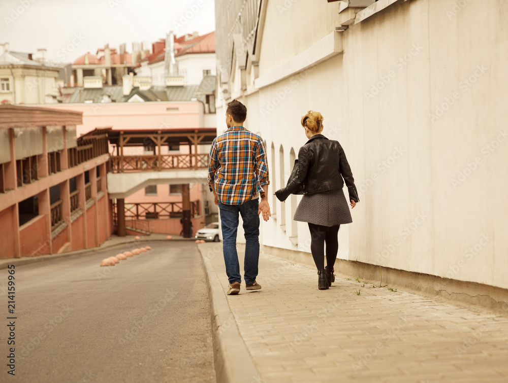 rear view of loving young couple walking down the street rear view of loving young couple walking down the street