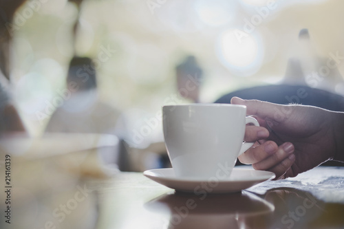 Close up woman hands holding a cup of coffee over wooden table