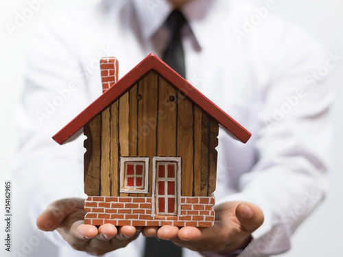 Business man hand holding wooden house