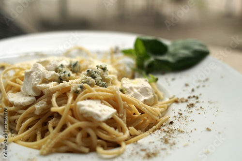 Spaghetti with basil & white cheese on top, close up