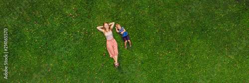 Fotografie Mom and son are lying on the grass in the park, photos from the drone, quadracop