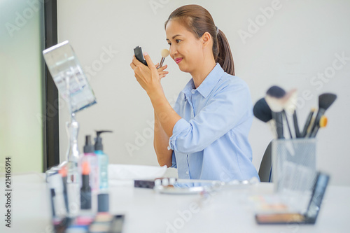 Woman making a video for her blog on cosmetics using digital camera. Young female blogger on camera screen holding cosmetics.