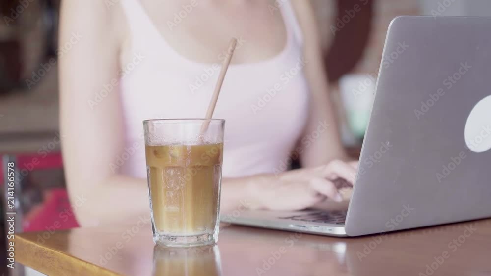 Young woman working on a laptop computer and drinking coffee Young woman working on a laptop computer and drinking coffee