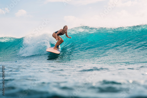 Surf woman on surfboard during surfing. Surfer and ocean wave