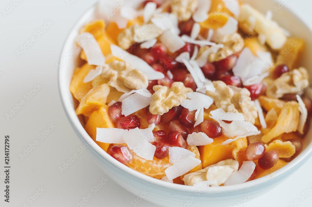 Healthy vegan salad. Mango, tangerine, banana, dried apricot, walnut, coconut flakes, pomegranate in a bowl. Healthy fruit dessert Healthy vegan salad. Mango, tangerine, banana, dried apricot, walnut, coconut flakes, pomegranate in a bowl. Healthy fruit dessert