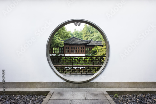 Traditional Chinese house viewed through a circular moon gate in a Chinese garden