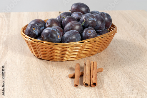 Cinnamon in front of a basket full of ripe plums