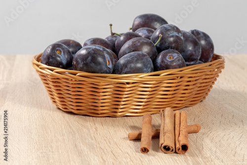 Cinnamon in front of a basket full of ripe plums