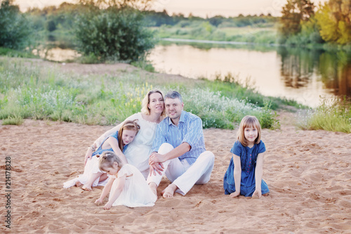 Fototapeta Naklejka Na Ścianę i Meble -  happy family sitting on sand by river