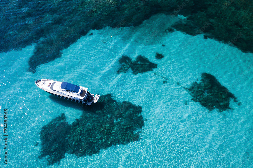 Aerial view of a yacht on an emerald and transparent Mediterranean sea. Emerard coast (Costa Smeralda), Sardinia, Italy.