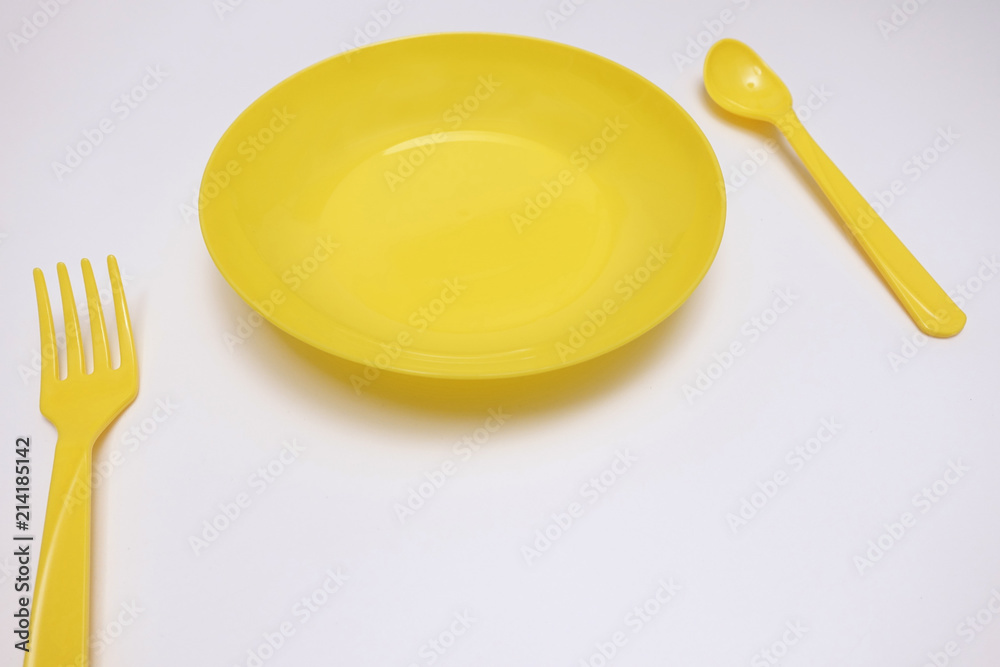 Set of a yellow plate, spoon and fork isolated on white background Set of a yellow plate, spoon and fork isolated on white background