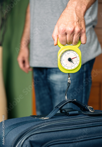 Принти на полотні Man checking hand luggage weight using a steelyard balance by low cost airlines