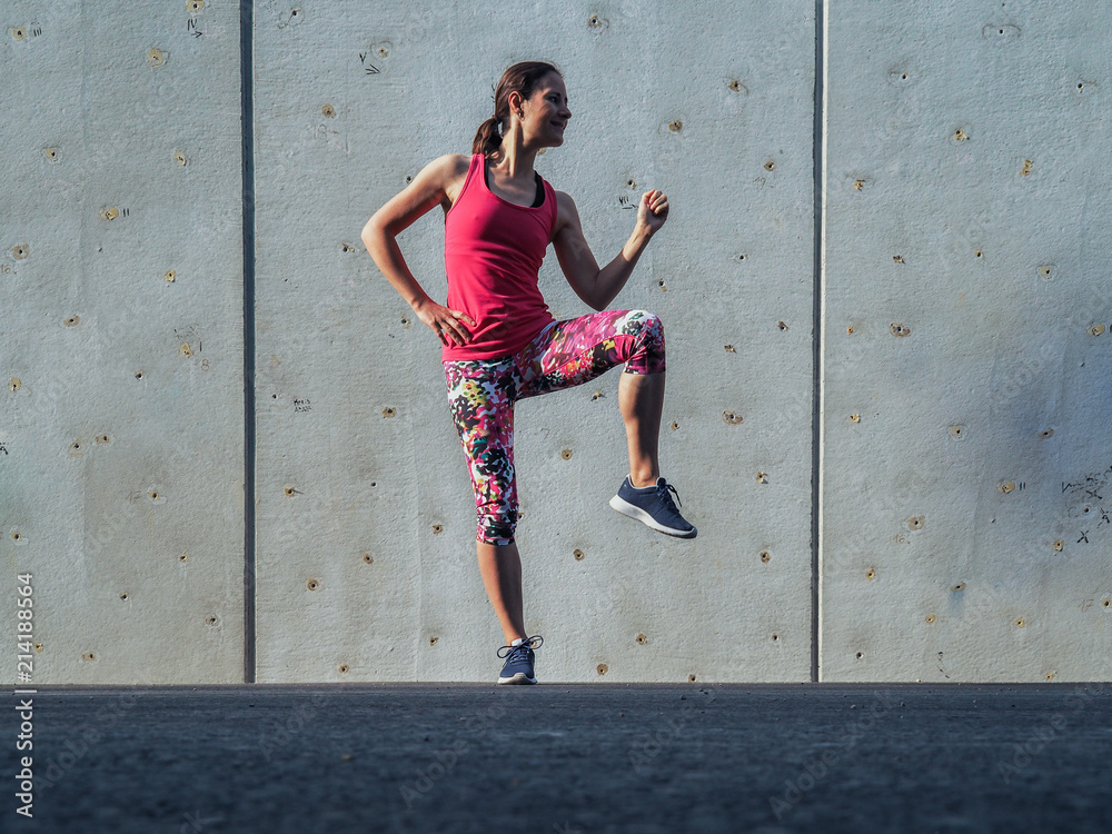 fitness lady making balance Pose outdoor infront of a grey cement wall as background