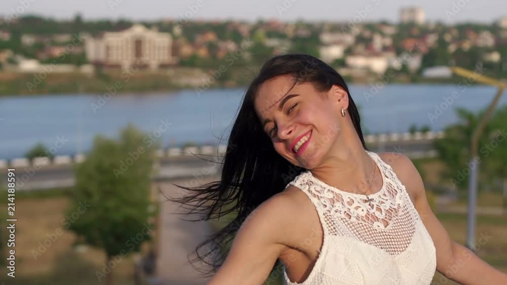 Portrait of a young beautiful girl with blue eyes and long hair on the background of a beautiful landscape on the river and the city, she turns and looks at the camera. Portrait of a young beautiful girl with blue eyes and long hair on the background of a beautiful landscape on the river and the city, she turns and looks at the camera.