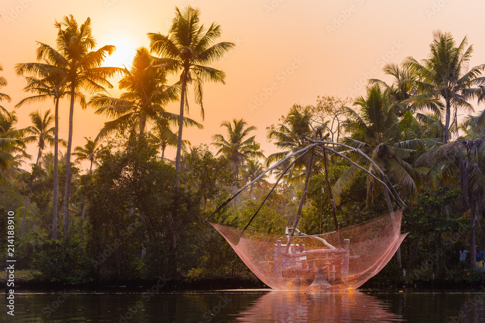 A traditional Chinese fishing net is raised in the sunset on a lake, Backwaters, Kerala state, India.