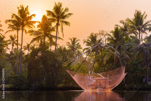 A traditional Chinese fishing net is raised in the sunset on a lake, Backwaters, Kerala state, India. photo