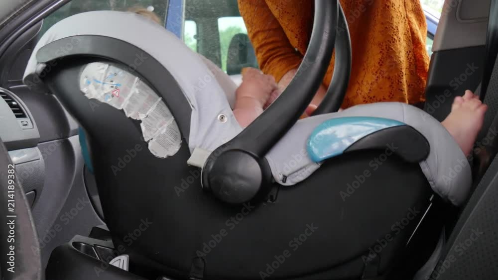 mom puts the child in the car seat and fasten seat belts Stock Video ...