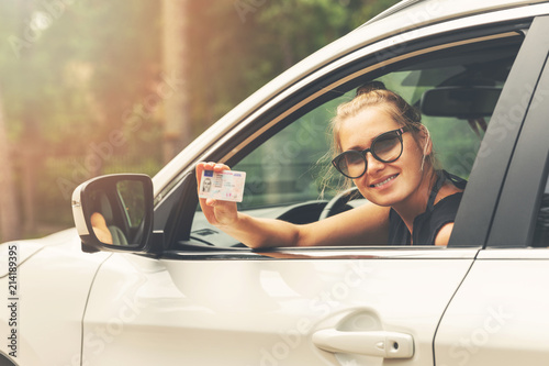 Cuadro en lienzo smiling attractive woman showing her driver license out of car window