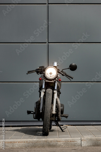 Vintage motorbike parking near gray wall of finance building. Everything is ready for having fun driving the empty road on a motorcycle tour journey. Businessman hobby. Space for your individual text.