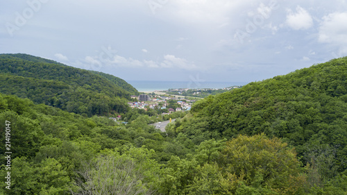 Aerial stock photo of car driving along the winding mountain pass road through the forest in Sochi, Russia. People traveling, road trip on curvy road through beautiful countryside scenery.