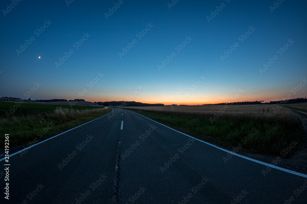 Straße durch Felder im Sonnenuntergang