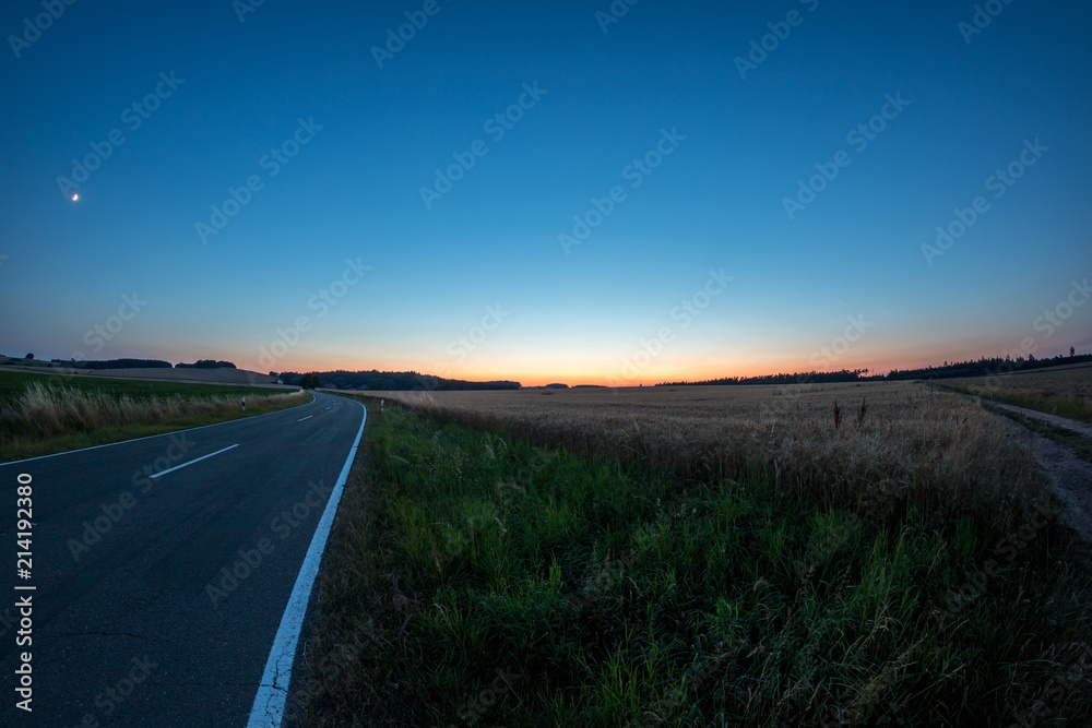 Straße durch Felder im Sonnenuntergang
