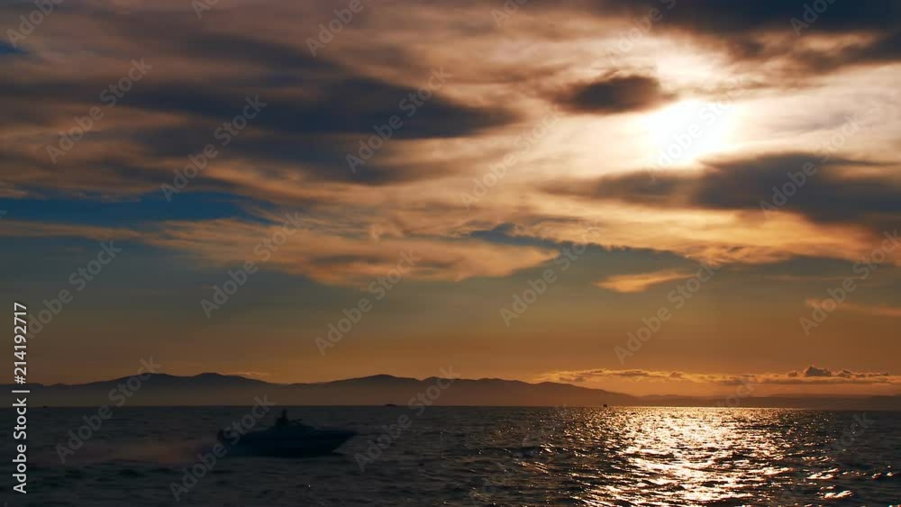 A beautiful sunset in the clouds, on the surface of the ocean, the waves shine brightly in the sun, far away is the mountains in light evening haze. Color correction options A beautiful sunset in the clouds, on the surface of the ocean, the waves shine brightly in the sun, far away is the mountains in light evening haze. Color correction options