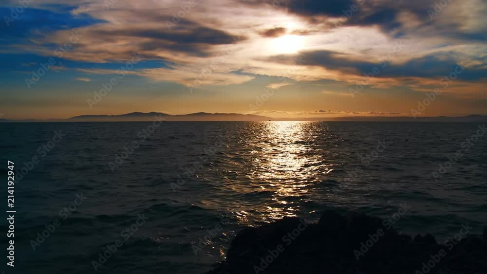 A beautiful sunset in the clouds, on the surface of the ocean, the waves shine brightly in the sun, far away is the mountains in light evening haze. Color correction options A beautiful sunset in the clouds, on the surface of the ocean, the waves shine brightly in the sun, far away is the mountains in light evening haze. Color correction options