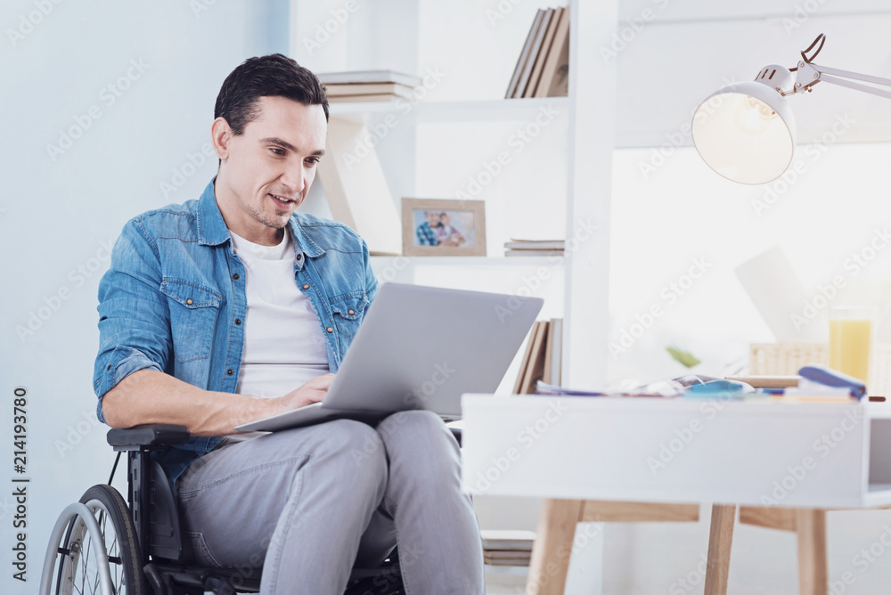 Freelance work. Pleased brunette keeping smile on his face while typing message Freelance work. Pleased brunette keeping smile on his face while typing message