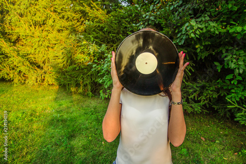 Girl holding a vinyl record in her hands  covering her face