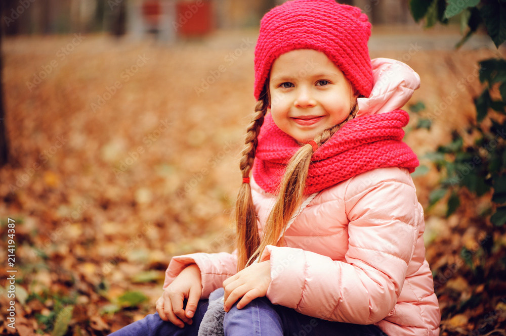 autumn portrait of smiling child girl enjoying the walk in sunny park in warm knitted hat and scarf autumn portrait of smiling child girl enjoying the walk in sunny park in warm knitted hat and scarf