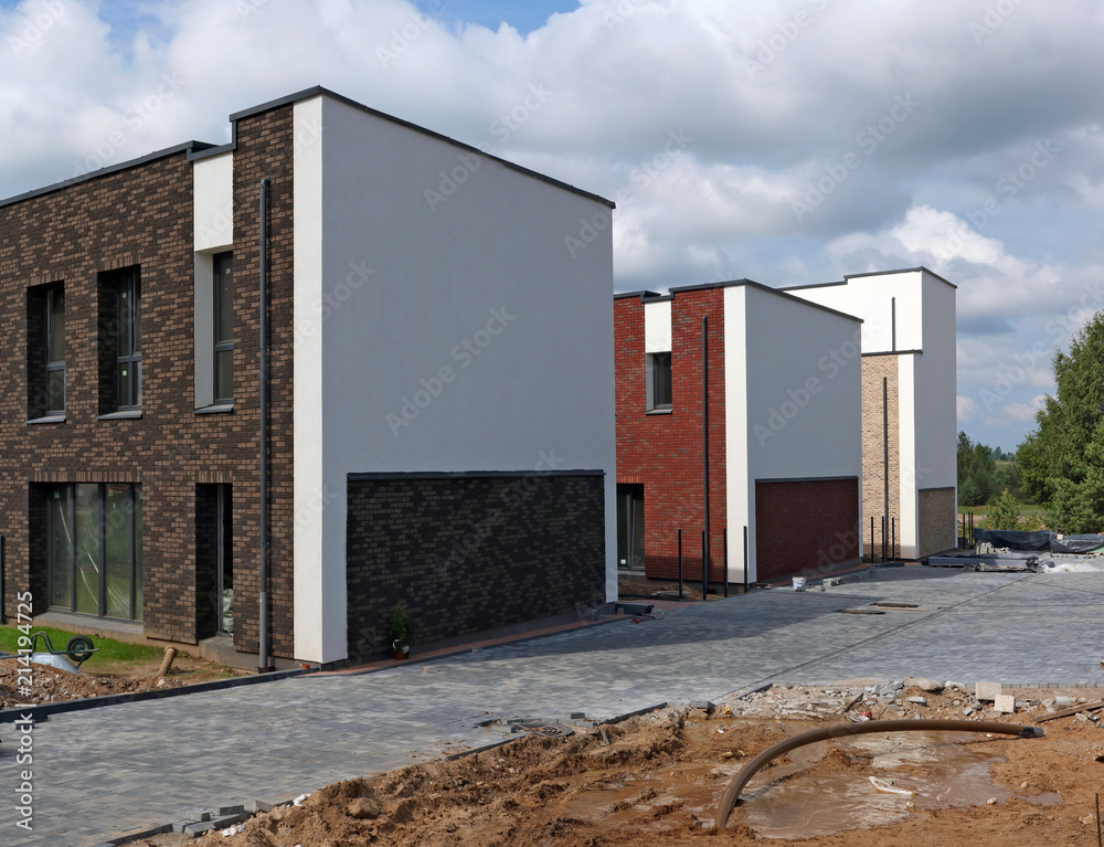 New mass production standard houses in the forest are built on clay and sand.  Sunny summer day urban landscape.