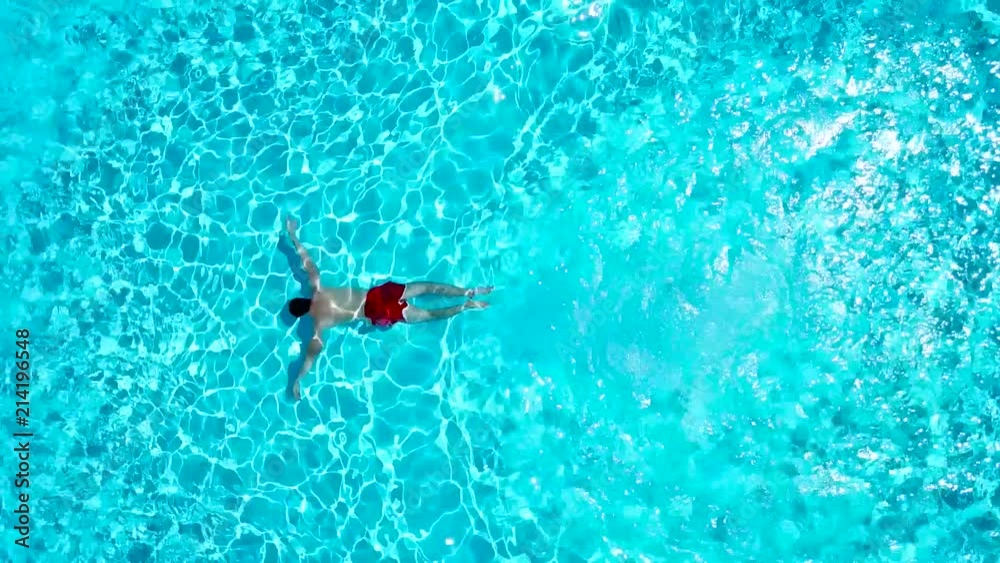 View from the top as a man jumping and dives into the pool and swims under the water