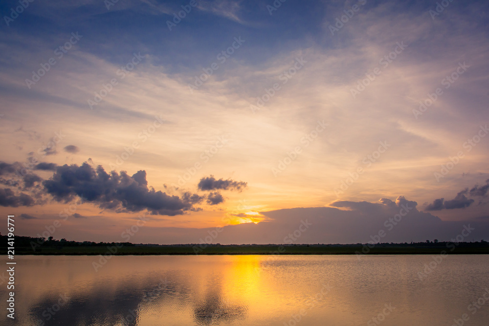 Sunset in the lake. beautiful sunset behind the clouds above the over lake landscape background