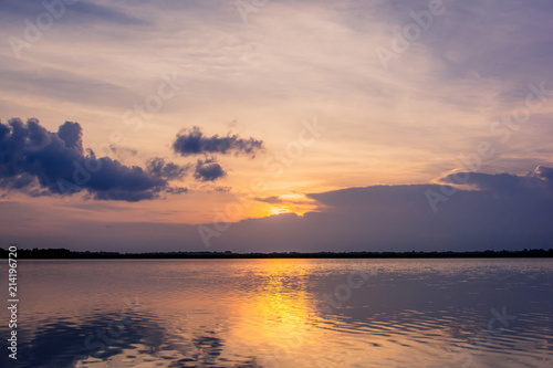 Sunset in the lake. beautiful sunset behind the clouds above the over lake landscape background