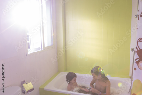 Slika na platnu Happy laughing sister kids taking a bath playing with foam bubbles