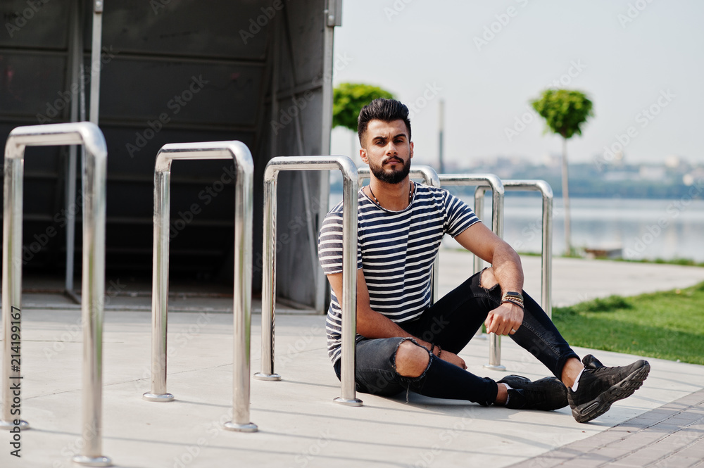 Fototapeta premium Handsome tall arabian beard man model at stripped shirt posed outdoor. Fashionable arab guy.