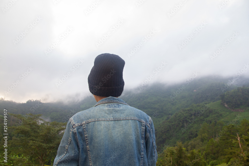 Asian young man in Jean jecket and black hat hiking at mountain peak above clouds and fog Hiker outdoor. Doi Luang Chiang Dao Chiang Mai Province,In morning. Asian young man in Jean jecket and black hat hiking at mountain peak above clouds and fog Hiker outdoor. Doi Luang Chiang Dao Chiang Mai Province,In morning.