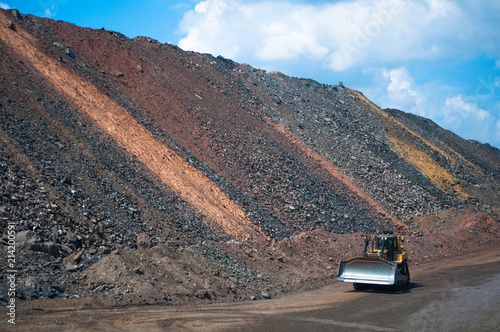 bulldozer moving along the road in the iron ore quarry. colored embankment.