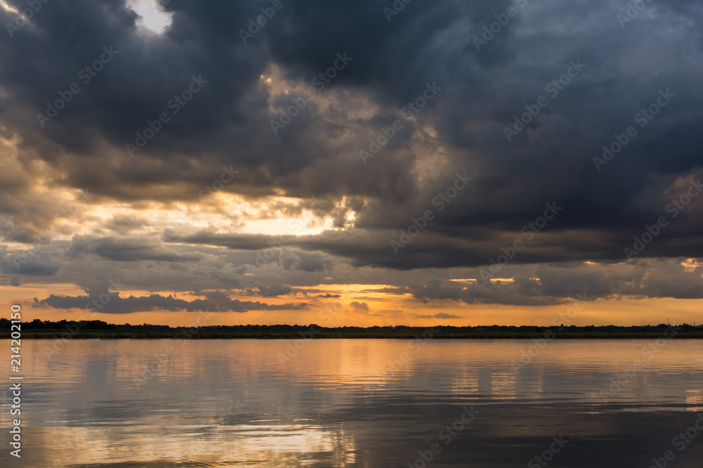 Sunset in the lake. Beautiful sunset behind the storm clouds before a thunder storm above the over lake landscape background. Dramatic sky with cloud at sunset. Sunset in the lake. Beautiful sunset behind the storm clouds before a thunder storm above the over lake landscape background. Dramatic sky with cloud at sunset.
